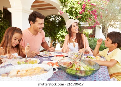 Hispanic Family Enjoying Outdoor Meal At Home Together