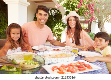 Hispanic Family Enjoying Outdoor Meal At Home Together