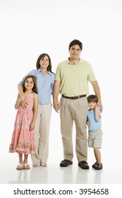 Hispanic Family Of Four Standing Against White Background.