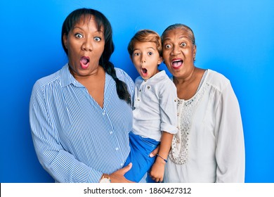 Hispanic Family Of Grandmother, Mother And Son Hugging Together Scared And Amazed With Open Mouth For Surprise, Disbelief Face 