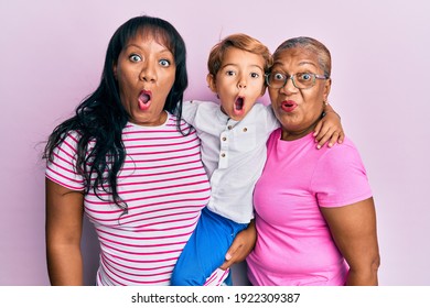 Hispanic Family Of Grandmother, Mother And Son Hugging Together Scared And Amazed With Open Mouth For Surprise, Disbelief Face 