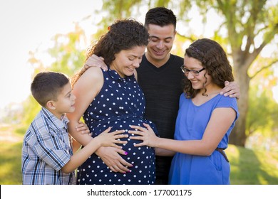 Hispanic Family Hands On Pregnant Mother Tummy Feeling Baby Kick Outdoors At The Park.