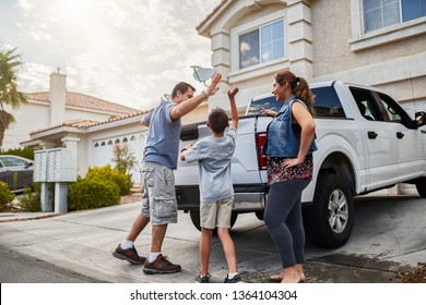 Hispanic Family Loading Luggage Into Back Of Pickup Truck In Front Of House For Travel