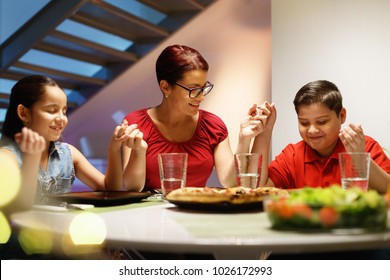 Hispanic Family With Mom, Son And Daughter Praying Before Having Dinner At Home. Latino People With Mother, Boy And Girl During Meal. Nutrition, Food And Religion