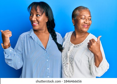 Hispanic Family Of Mother And Daughter Hugging Together With Love Pointing Thumb Up To The Side Smiling Happy With Open Mouth 