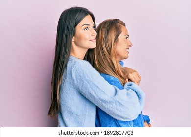 Hispanic Family Of Mother And Daughter Wearing Wool Winter Sweater Looking To Side, Relax Profile Pose With Natural Face And Confident Smile. 