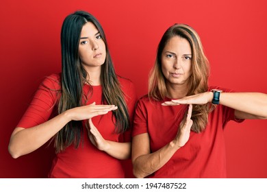 Hispanic Family Of Mother And Daughter Wearing Casual Clothes Over Red Background Doing Time Out Gesture With Hands, Frustrated And Serious Face 