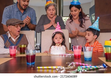 Hispanic family: parents, grandparents and grandchildren get together to celebrate a girl's birthday.
The girl blows out her candle and makes a wish. - Powered by Shutterstock