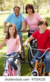 Hispanic Family Riding Bikes In Park