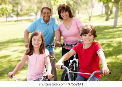 Hispanic Family Riding Bikes In Park