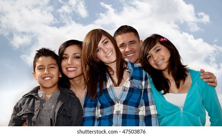 Hispanic Family Seated Against A Cloudy Sky