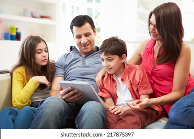 Hispanic Family Sitting On Sofa Using Digital Tablet