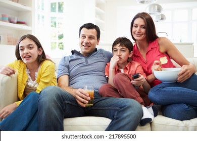 Hispanic Family Sitting On Sofa Watching TV Together