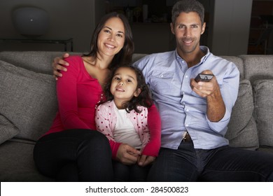 Hispanic Family Sitting On Sofa And Watching TV