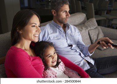 Hispanic Family Sitting On Sofa And Watching TV