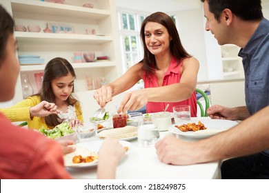 Hispanic Family Sitting At Table Eating Meal Together