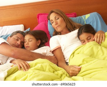 Hispanic Family Sleeping Together In Bed.