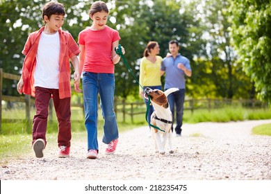 Hispanic Family Taking Dog For Walk In Countryside