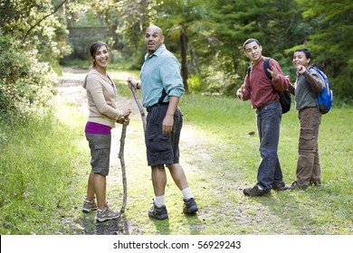 Hispanic Family With Two Boys Hiking In Woods On Trail