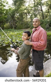 Hispanic Father And 10 Year Old Son Fishing In Pond