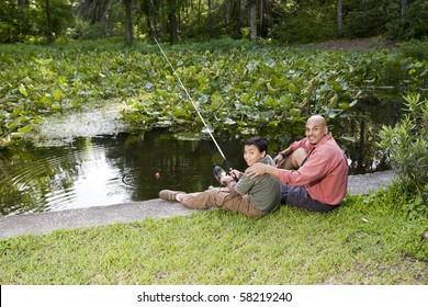 Hispanic Father And 10 Year Old Son Fishing In Pond