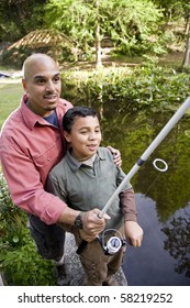 Hispanic Father And 10 Year Old Son Fishing In Pond