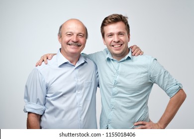 Hispanic father and adult son hugging and smiling at camera. Good famile relations.