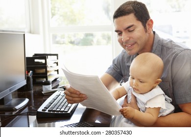 Hispanic father with baby working in home office