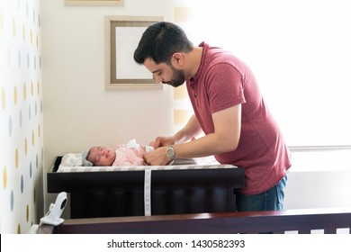 Hispanic father changing newborn daughter's diaper - Powered by Shutterstock