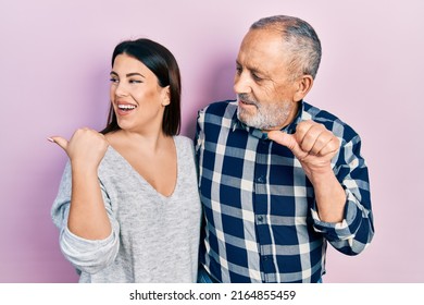 Hispanic Father And Daughter Wearing Casual Clothes Smiling With Happy Face Looking And Pointing To The Side With Thumb Up. 