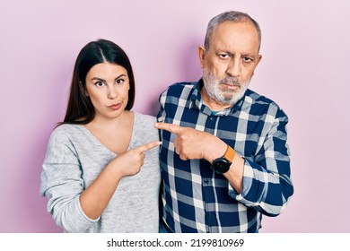 Hispanic Father And Daughter Wearing Casual Clothes Pointing With Hand Finger To The Side Showing Advertisement, Serious And Calm Face 