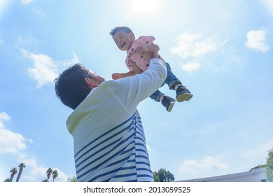 Hispanic Father Holding His Little Baby In The Air In The Park, Close Up