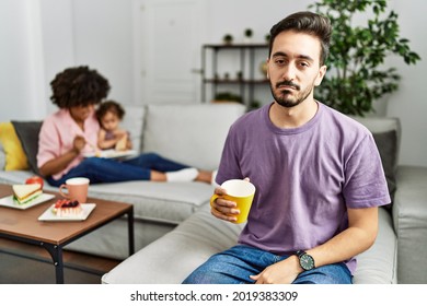 Hispanic Father Of Interracial Family Drinking A Cup Coffee Looking Sleepy And Tired, Exhausted For Fatigue And Hangover, Lazy Eyes In The Morning. 