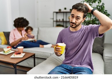 Hispanic Father Of Interracial Family Drinking A Cup Coffee Confuse And Wondering About Question. Uncertain With Doubt, Thinking With Hand On Head. Pensive Concept. 