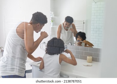 Hispanic Father And Son Brushing Teeth Together In Front Of Mirror In Bathroom. Unaltered, Family, Togetherness, Hygiene And Routine Concept.