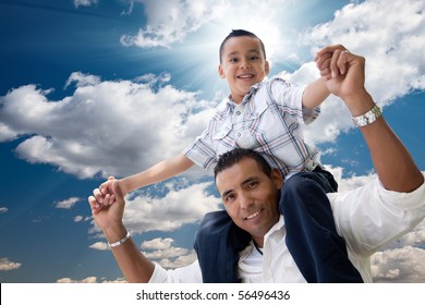 Hispanic Father And Son Having Fun Over Clouds And Blue Sky With Sun Rays.