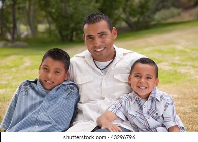 Hispanic Father And Sons Portrait In The Park.