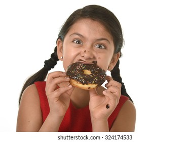 Hispanic Female Child In Red Dress Eating Chocolate Donut With Hands And Mouth Stained And Dirty Smiling Happy In Kid Loving Sugar And Sweet Food Concept