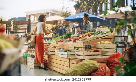 Hispanic Female Customer Buying Two Garlic Heads and a Pineapple From a Multiethnic Farmers Couple. Successful Adults Managing Small Business Farm Stall at a City Square Market - Powered by Shutterstock