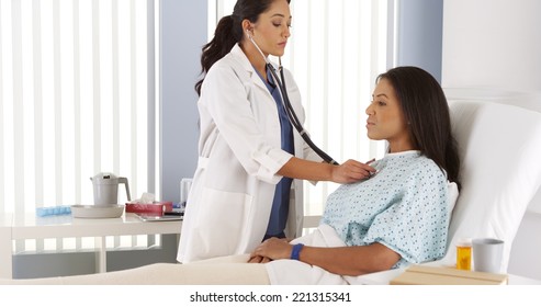 Hispanic Female Doctor Listening To Patient With Stethoscope