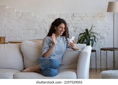 Hispanic Female Make Videocall Use App On Cellphone Sit On Sofa At Home. Beautiful Woman Enjoy Distance Talk To Family Or Friend Greeting Boyfriend Start Videoconference, Virtual Meeting Event Concept