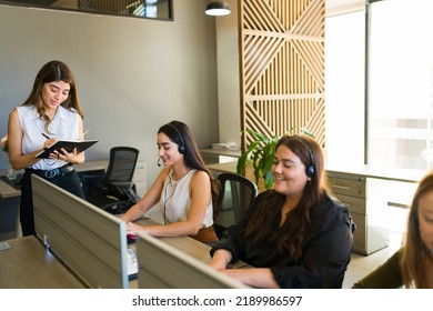 Hispanic female manager and boss talking with female co-workers about customer support at the call center - Powered by Shutterstock