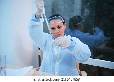 Hispanic Female Scientist Pharmacologist In Protective Lab Coat, Using A Glass Graduated Pipette, Titling A Chemical Substance Into A Test Tube, Making Clinical Study In A Medical Research