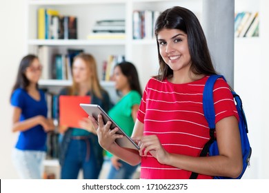Hispanic female student with tablet computer with group of multi ethnic college students at classroom of university