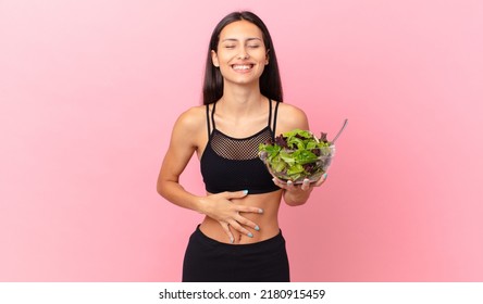 Hispanic Fitness Woman Laughing Out Loud At Some Hilarious Joke And Holding A Salad