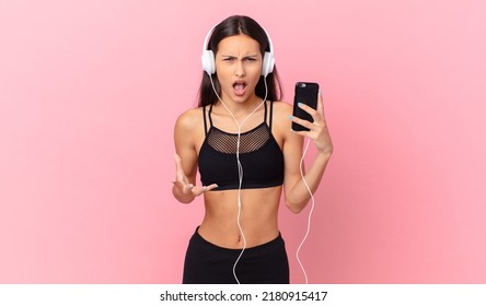 Hispanic Fitness Woman Looking Angry, Annoyed And Frustrated With Headphones And A Phone