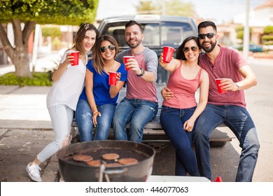 Hispanic Friends Sitting In The Back Of A Pick Up Truck And Tailgating While Drinking Cold Beers Outside