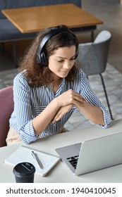 Hispanic Girl College Student Wearing Headphones Watching Distance Online Learning Web Class, Remote University Webinar Or Having Talk On Laptop Video Call Virtual Meeting Seminar At Home Or Campus.