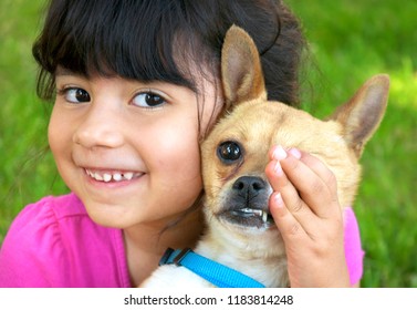 Hispanic girl holding and covering the eye of her chihuahua