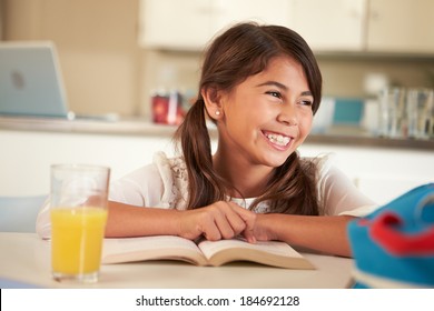 Hispanic Girl With Reading Homework At Table